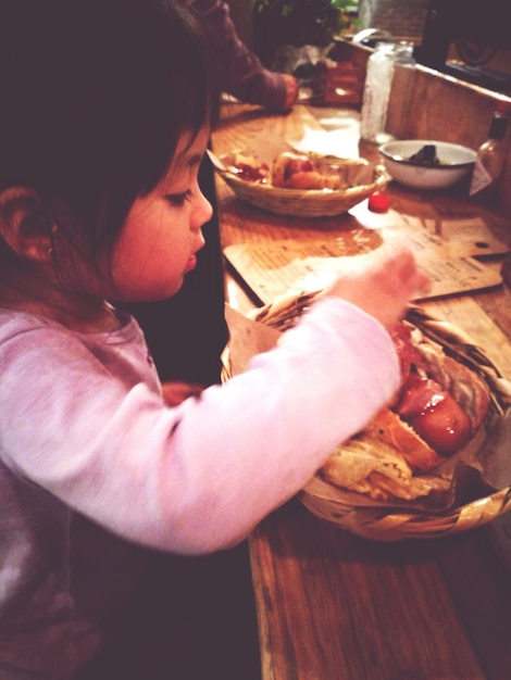 Foto vista laterale di una ragazza che mangia un pasto in un cesto di vimini in un ristorante