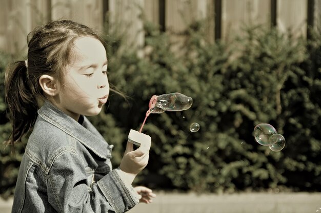 Photo side view of girl holding bubbles