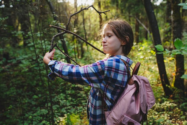 Side view of girl holding sticks at forest