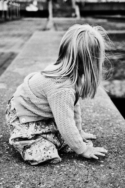 Photo side view of girl kneeling on footpath