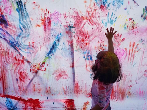 Foto vista laterale di una ragazza che dipinge un muro durante holi