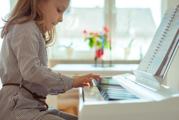 Foto vista laterale di una ragazza che suona il pianoforte