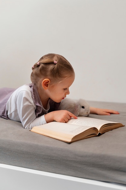 Side view girl reading with bunny