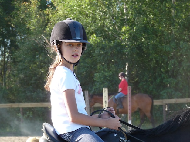 Photo side view of girl riding horse