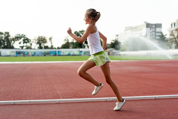 Foto vista laterale della ragazza sulla pista di atletica