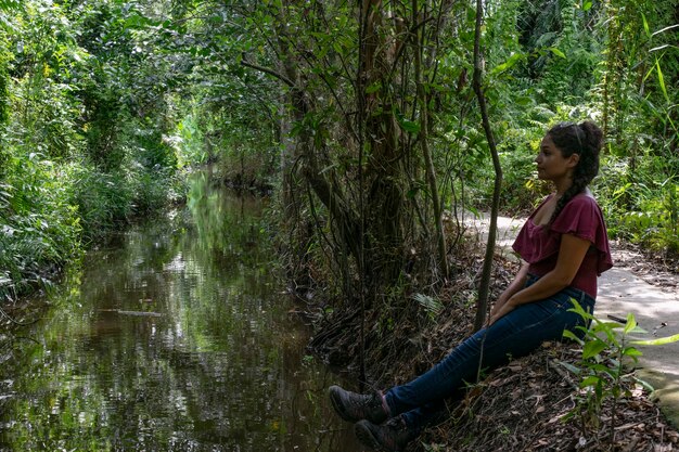 Foto vista laterale di una ragazza seduta su una pianta nella foresta