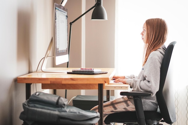 side view of girl using computer at home