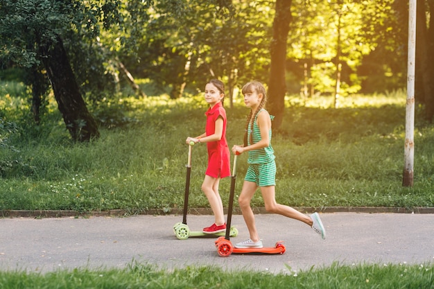 Photo side view of a girls riding kick scooter in the park