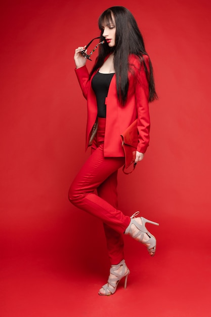 Side view of glamorous brunette posing in red suit