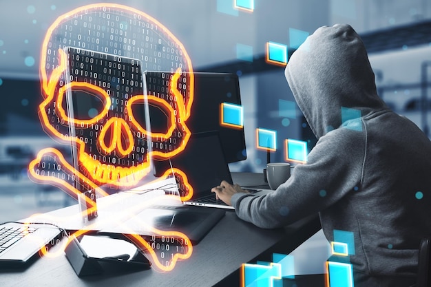 Side view of hacker at desk using computers with glowing digital binary code skull on blurry office interior background Hacking piracy malware and data theft concept Double exposure