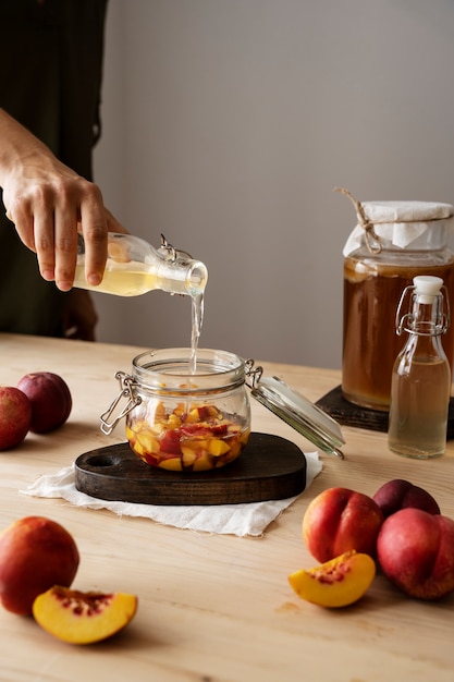 Photo side view hand pouring kombucha in jar