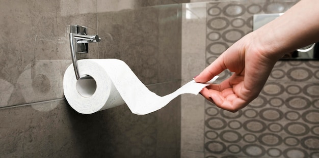 Side view hand pulling toilet paper