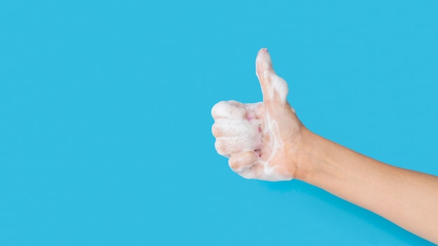 Photo side view of hand with foam from soap and thumbs up