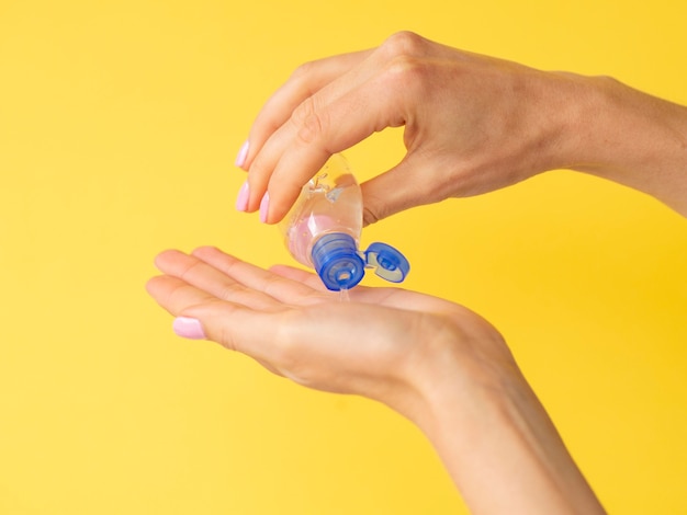 Photo side view of hands using hand sanitizer