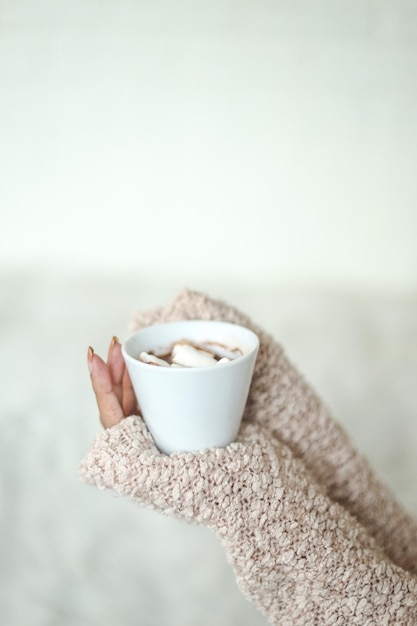 Side view of hands of woman in sweater holds hot drink Seasonal comforting beverage hygge concept