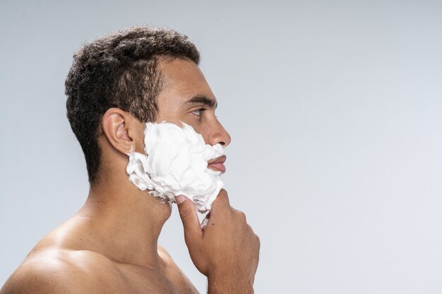 Side view of a handsome male rubbing his chin with shaving foam on it