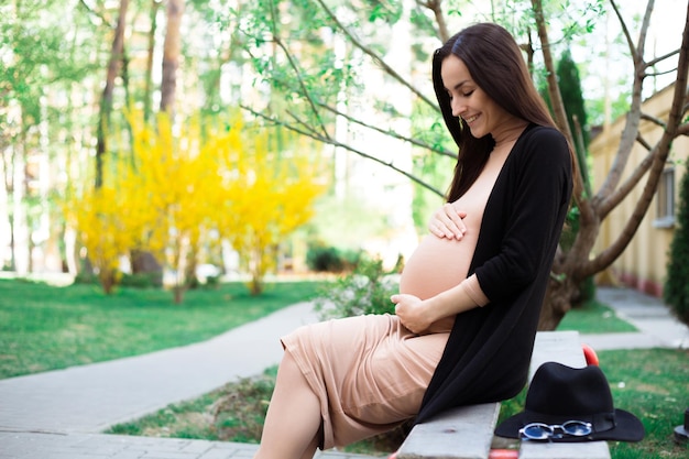 벤치에 앉아 행복 한 아름 다운 임신한 여자의 측면 보기