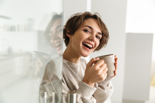 Side view of Happy brunette woman drinking coffee at home