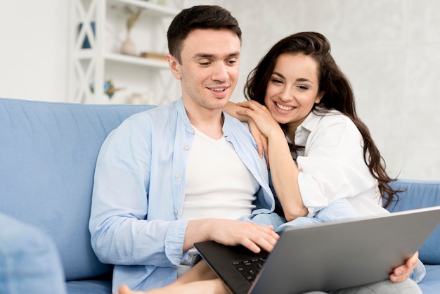 Photo side view of happy couple at home with laptop