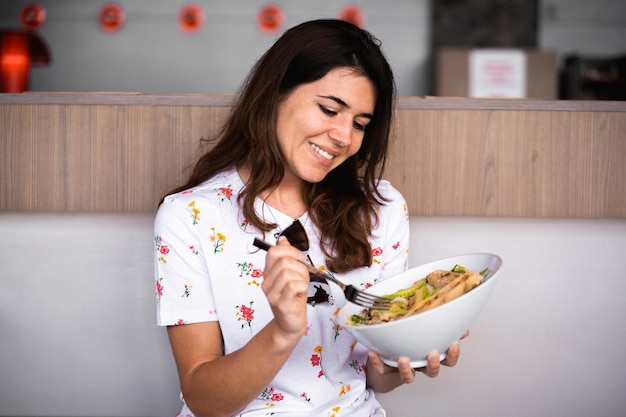 Side view happy female enjoys eating a healthy meal with mixed salad