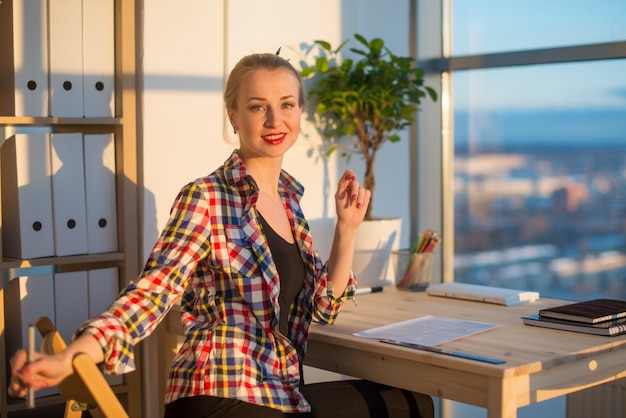 Side view of happy young woman working in home office, writing on paper.