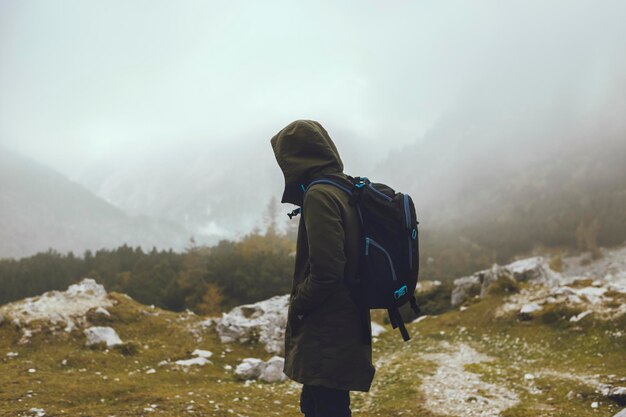 Side view of hiker with backpack standing on mountain