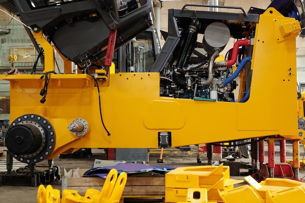 Photo side view of huge industrial machine of yellow color with open engine