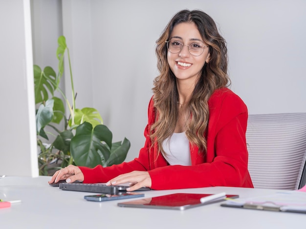 オフィスで机に座っている自信のある若い白人の茶色の女性のサイドビュー画像