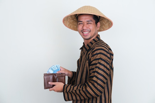 インドネシアの伝統的な農夫が財布からお金を取りながら幸せそうに笑っている側面図