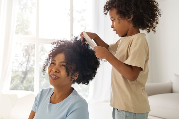 Foto bambino di vista laterale che spazzola i capelli della madre