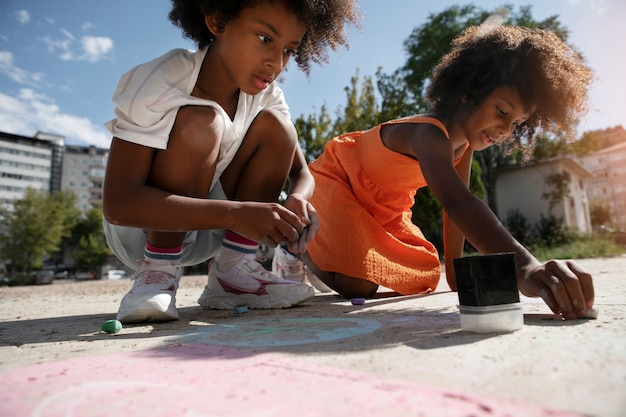 写真 舗装に絵を描く側面図の子供たち