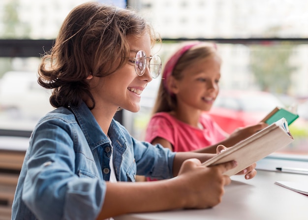 Bambini di vista laterale che imparano nella biblioteca