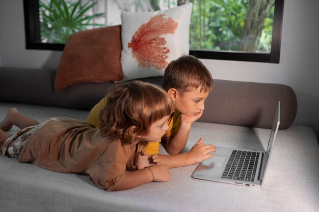 Photo side view kids looking at laptop