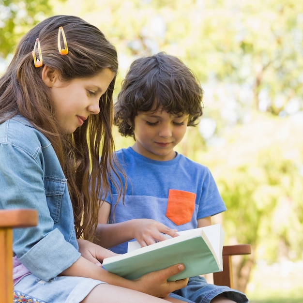 Side view of kids reading book on park bench