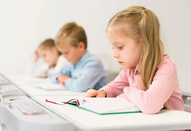 Bambini di vista laterale che leggono la loro lezione