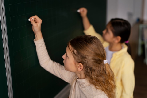 Photo side view kids writing on board