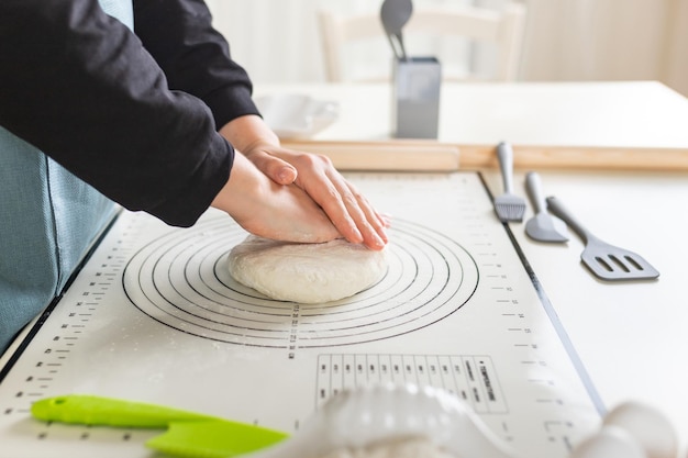 Side view of kneading dough on rubber kitchen mat on kitchen table