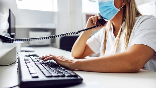 Side view lab assistant sitting in laboratory and having emergency call about covid-19 positive patient.