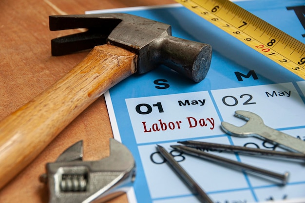 Side view of Labor Day text on torn paper with calendar and working tools background Labor day concept