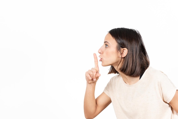 Side view of a latin woman asking for silence with the finger on her mouth.