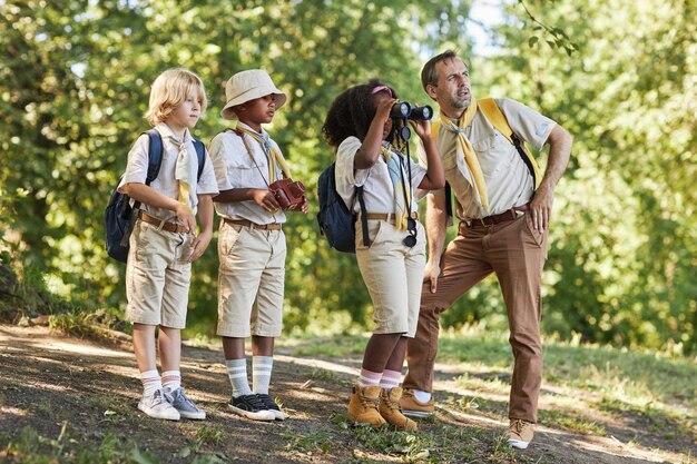 Photo side view little girl scout looking in binoculars