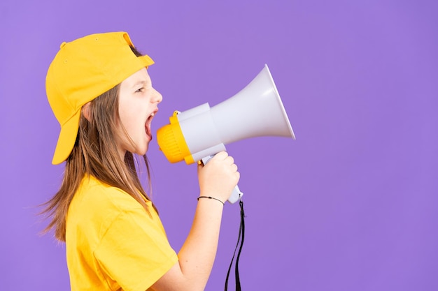 Side view of little girl shouting on megaphone