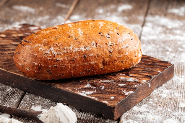 Side view on a loaf of white wheat bread on a wooden board