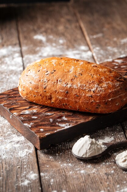 Side view on a loaf of white wheat bread on a wooden board