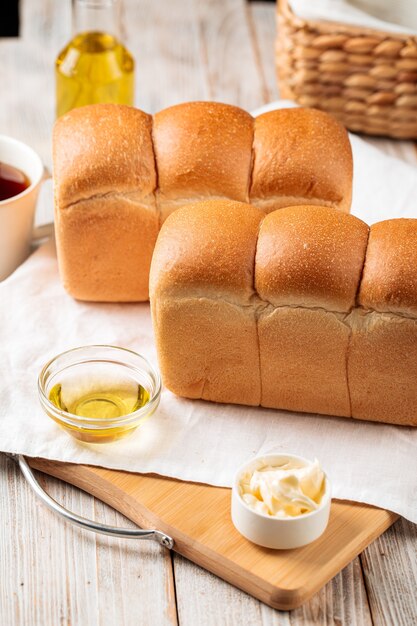 Side view on loafs of fresh baked shaped wheat bread with butter and coffee