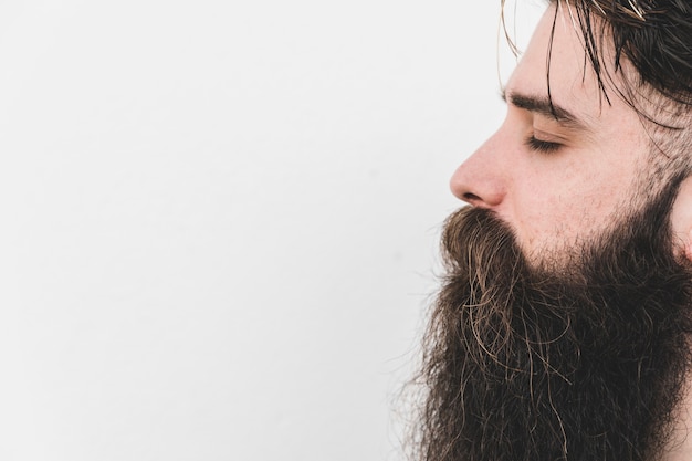 Photo side view of a long bearded man closing his eye against white backdrop