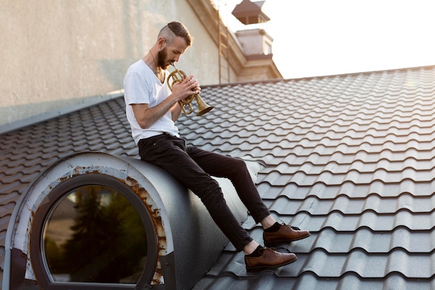 Side view of male artist playing the cornet on roof top