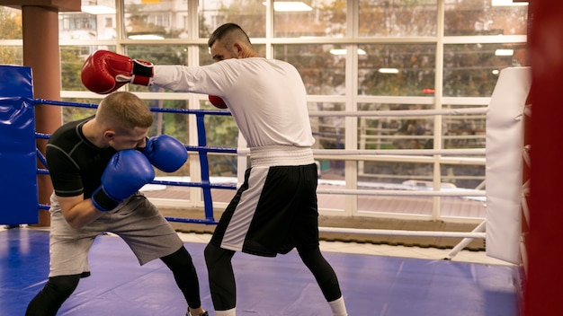 Photo side view of male boxer practicing with trainer