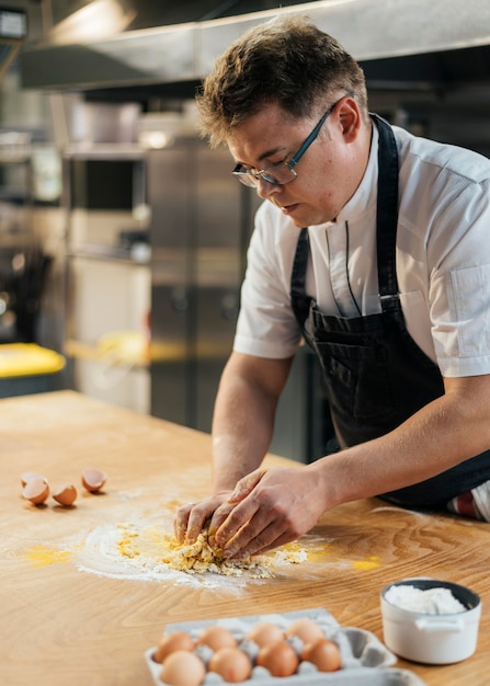 Side view of male chef making dough