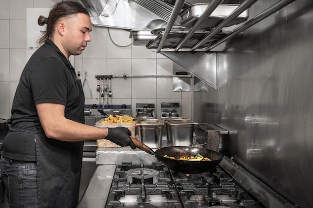 Foto vista laterale di uno chef maschio che lavora in una cucina commerciale